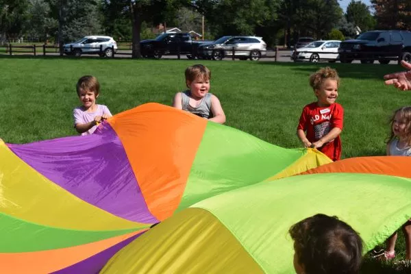 children holding a blanket to move the ball on top